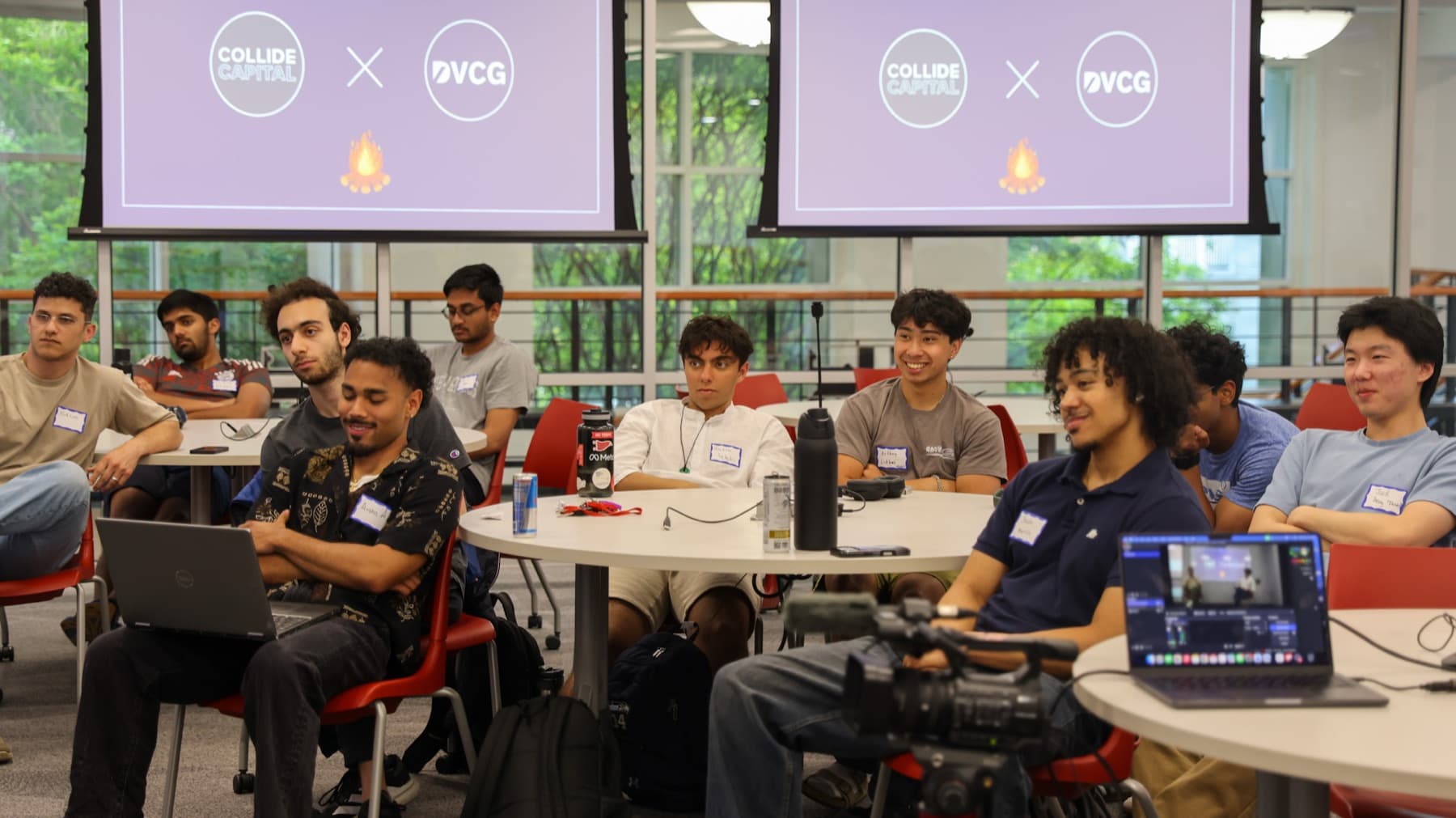 A full room at the Collide Capital and DVCG event, both logos on screen behind the speakers