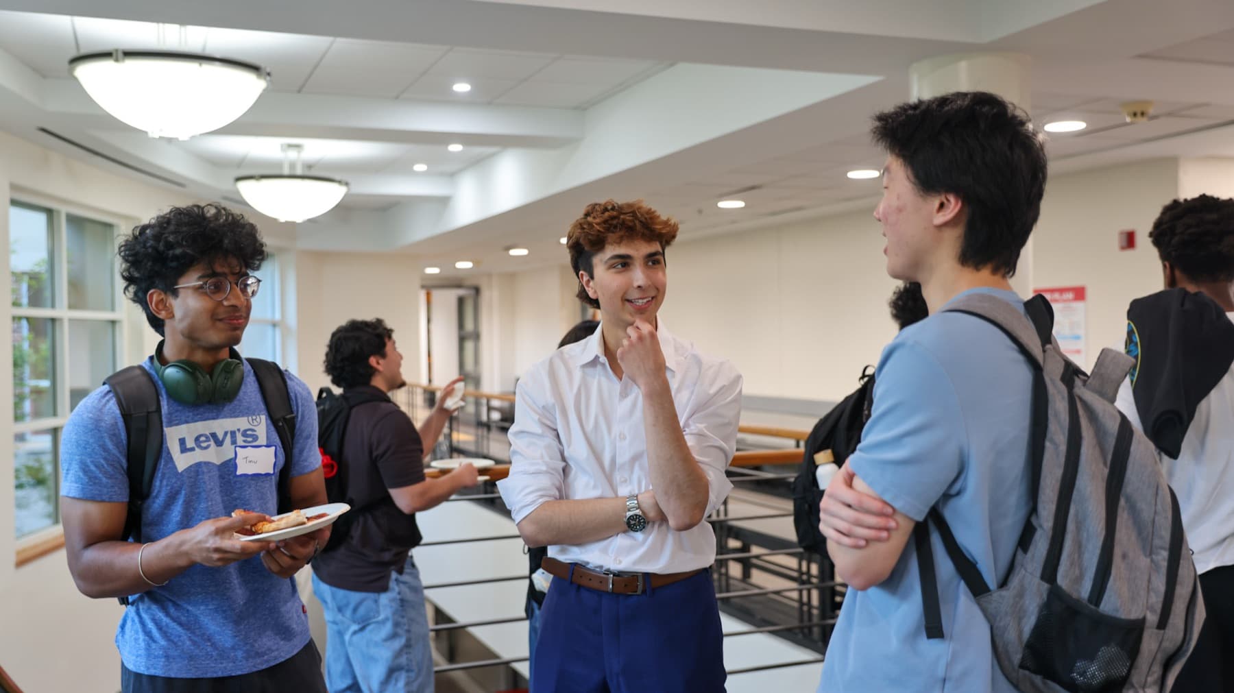 Students talking in the hallway after a DVCG session, name tags on